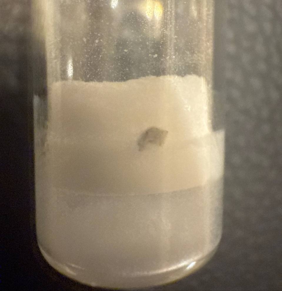 A dark patch visible against white solid inside a vial