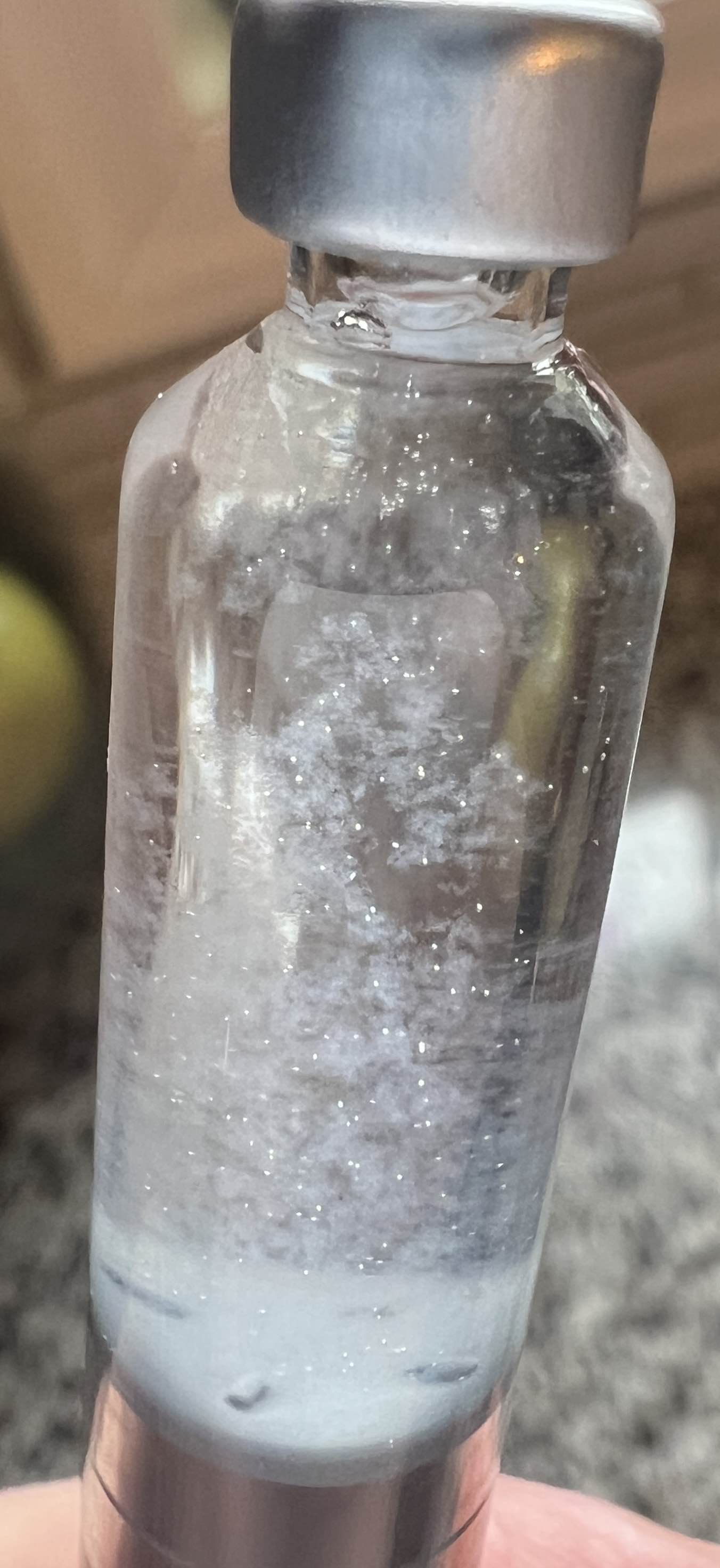 An inverted vial with irregular translucent material and bubbles